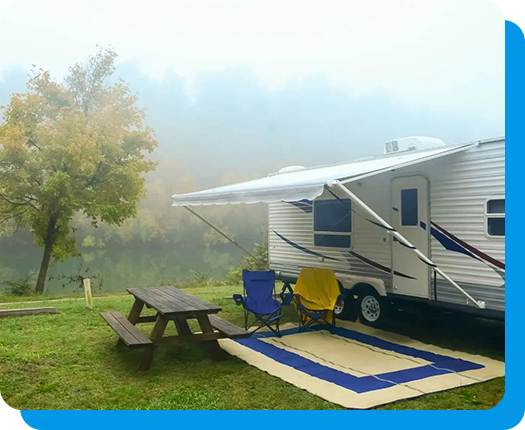 A camping trailer with picnic table and chairs.